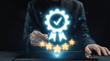 Profesyonel bir el, yıldızlı parlak bir sertifika simgesi ve tablet üzerindeki bir işaret, dijital biçimlerdeki başarıyı, kaliteyi ve başarıyı simgeliyor. Dörtgen
