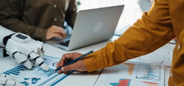 Bir insan eli çizelgeye robot bir el çizerken insan yaratıcılığının sinerjisini ve modern bir ofiste ileri teknolojiyi temsil eder. Noogenesis