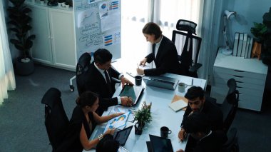 Toplantı odasındaki tabletten finansal istatistiklere bakan akıllı yöneticinin en üst görüntüsü. Masadaki yatırım verilerini not defteriyle analiz etmek için birlikte çalışan bir grup iş adamı. Müdürlük.