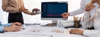 İç mimar tasarımcı grubu, daha kesin tasarım için planlar ve dizüstü bilgisayar ekran mimari yazılımı üzerinde birlikte tartışıyorlar. Modern ev tasarımı ve yenileme. İçgörü