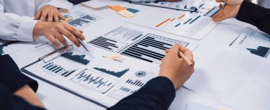 Collaborative teamwork focused on business strategy analysis features hands engaged with charts and graphs on a workspace table, reflecting data-driven discussions. SACTR