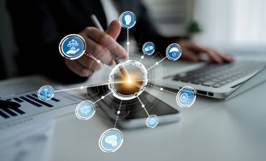 A modern workspace showcasing digital communication with business icons displayed over a mobile device and laptop, highlighting innovation and connectivity in a professional environment. Crux