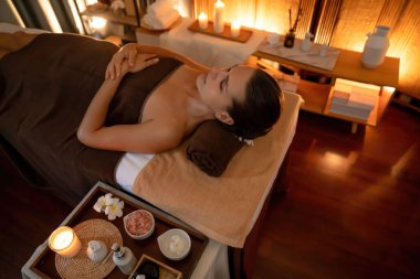Beyaz kadın müşteri stres önleyici spa masajının keyfini çıkarıyor ve lüks otel ya da otelde sıcak mum ışığında güzellik teniyle eğleniyor. Sessiz.