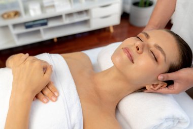 Kafkasyalı kadın stres önleyici kafa masajından ve lüks tatil beldesi ya da otel spa salonundaki modern ışık ortamında yüz güzelliği eğlencelerini şımartmaktan hoşlanıyor. Sessiz.