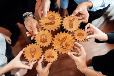 A diverse group of hands holding wooden gears with eco-friendly icons, symbolizing teamwork in sustainable business practices and innovative growth strategies for a better future. Amity