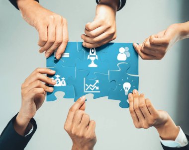 A group of diverse hands collaboratively assembling puzzle pieces, representing teamwork, innovative ideas, and strategic efforts to achieve common business goals and solutions. Amity