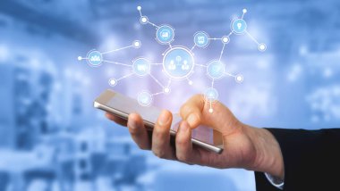 A hand holding a smartphone with a digital interface showcasing various icons that symbolize communication and technology trends within a professional environment. Tessel