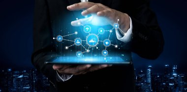 A businessman in a suit interacts with a tablet showcasing digital data visualization. The background displays a dark cityscape, symbolizing innovation and technology. Tessel