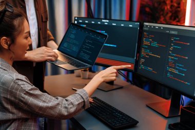 Modern ofisteki neon ışık odasında bilgi ağını gösteren dizüstü bilgisayarla iki ekranda veri çalıştıran akıllı web sitesi geliştirme kodlayıcı sistemini tartışan IT geliştiricilerinin ciddiyeti. İnfobahn.