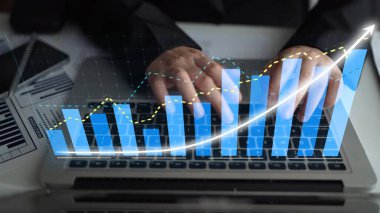 A modern setup shows hands typing on a laptop with visual graphs representing data analysis, business growth, and financial insights in today digital economy. Copula