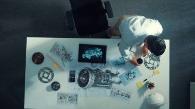 Motoru öğrenirken makinistlerin tablet tutuş tabletinin yukarıdan aşağıya görüntüsü. Masada yürürken tablete bakan ve türbin motorunu kontrol eden yetenekli proje yöneticisinin havadan görünüşü. Hizalama.