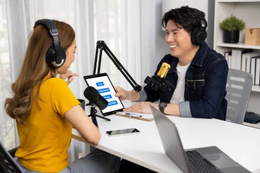 Gülümseyen radyo etkili sunucusu kulaklık takıyor kadın konuşmacı sosyal medya online canlı yayın kanalı ile röportaj yapıyor tablet ekranla konuşarak sabah stüdyo kaydındaki bağlantıyı paylaşıyor. İnfobahn.