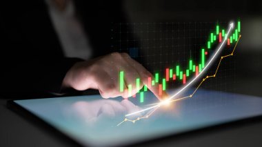 A business professional interacts with a digital touchscreen displaying a stock chart, emphasizing analysis of market trends in a modern office setting. Impute