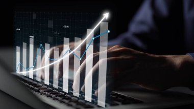 A business professional engages with a laptop, visualizing data trends and financial metrics through graphs and charts in a modern digital workspace. Copula