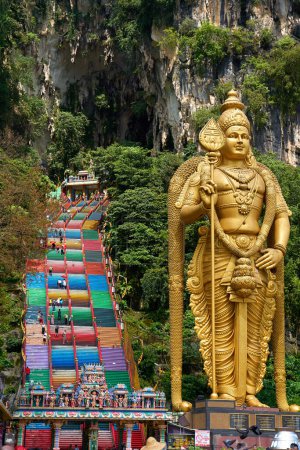 Photo for A huge golden statue of Lord Murugan at the entrance with multicolored steps to the Batu Caves. Kuala Lumpur, Malaysia - 11.09.2022 - Royalty Free Image