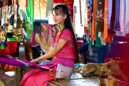 Téléchargez les photos : Portrait d'une femme d'une tribu à long cou, connue pour les anneaux métalliques autour de leur cou, tissant une couverture colorée. Célèbre la diversité culturelle et la tradition. Chiang Rai, Thaïlande - 09.02.2022 - en image libre de droit