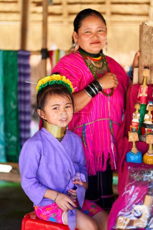 Téléchargez les photos : Femme de la tribu à long cou, connue pour les anneaux métalliques portés autour de leur cou, tenant son enfant. La photo capture le lien entre la mère et l'enfant et célèbre la diversité culturelle et la tradition. Chiang Rai, Thaïlande - 09.02.2022 - en image libre de droit