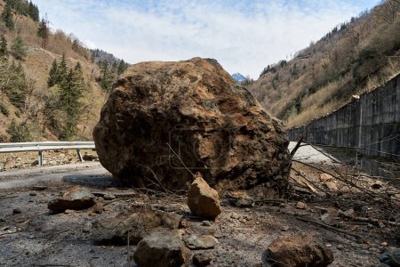 Foto de A huge rock fell from the mountains onto the road, destroying the asphalt and blocking half of the roadway. - Imagen libre de derechos