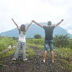 A young, happy couple in love poses in rice fields against the backdrop of Mount Agung volcano on the popular tourist island of Bali