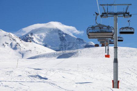 Foto de Remonte y pista de esquí en las montañas nevadas en el soleado día de invierno. Montañas del Cáucaso. Monte Tetnuldi, región de Svaneti, Georgia. - Imagen libre de derechos
