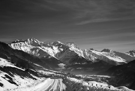 Téléchargez les photos : Route enneigée et montagne dans la brume au petit matin d'hiver. Montagnes du Caucase. Géorgie, région de Svaneti. Paysage tonique noir et blanc. - en image libre de droit