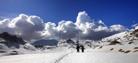 Photo for Panoramic view on snowy plateau with two hikers and blue sky with beautiful sunlight clouds. Turkey, Central Taurus Mountains, Aladaglar (Anti-Taurus), plateau Edigel (Yedi Goller) at spring. - Royalty Free Image