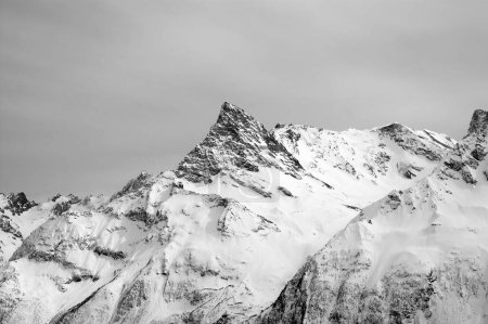 Photo for Black and white snowy mountains and grey cloudy sky. Caucasus Mountains in winter, region Dombay, Mount Belalakaya. - Royalty Free Image