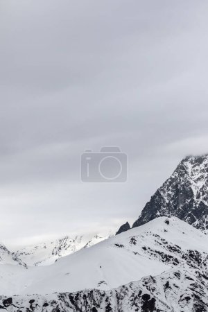 Snowy mountain pass and cloudy gray sky at winter evening. Caucasus Mountains, Svaneti region of Georgia.