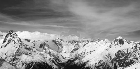 Panorama des schneebedeckten Winterberges in sonnigen Wolken. Kaukasus, Region Dombay. Schwarz-weiß getönte Landschaft