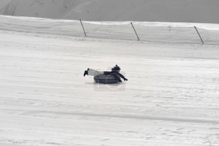 Foto de Niña cuesta abajo en el tubo de nieve en la estación de esquí en el sol día de invierno en las montañas nevadas. Imagen retro tonificada en blanco y negro - Imagen libre de derechos