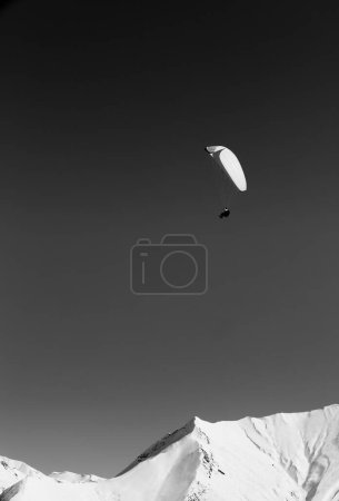 Foto de Paraglider in high snowy mountains at sun winter day. Caucasus Mountains, Georgia region Gudauri. Black and white toned image. - Imagen libre de derechos