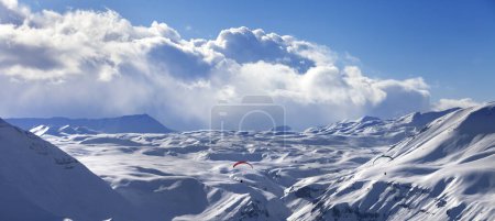 Foto de Speed flying in sun winter mountains. Snowy Caucasus Mountains at evening. Georgia, region Gudauri. Panoramic view - Imagen libre de derechos