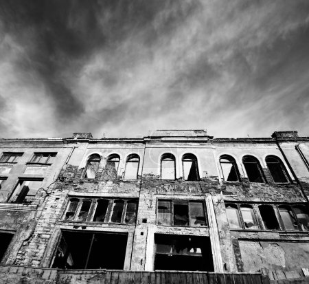 Téléchargez les photos : Black and white facade of old destroyed house with broken windows. Wide angle view. High contrast. - en image libre de droit