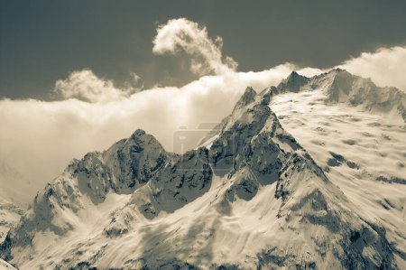 Foto de High winter snowy mountains in clouds. Caucasus Mountains, region Dombay. Retro color toned landscape. - Imagen libre de derechos