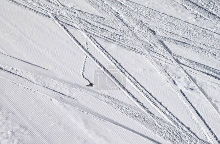 Foto de Pista de esquí nevada arreglada con trazas de esquís, tablas de snowboard y piedra en el día de invierno sol - Imagen libre de derechos