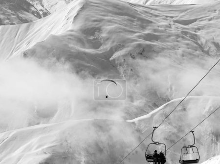 Foto de Telesilla y paraplano en la estación de esquí en el frío día de invierno. Montañas nevadas del Cáucaso en niebla. Georgia, región Gudauri. Paisaje tonificado blanco y negro - Imagen libre de derechos