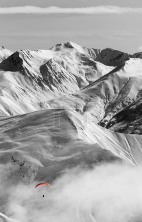 Foto de Parapente en las altas montañas nevadas en neblina. Montañas del Cáucaso en invierno. Georgia, región Gudauri. Imagen tonificada en blanco y negro. Efecto de color selectivo. - Imagen libre de derechos