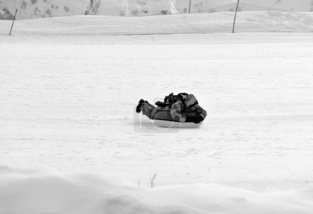 Foto de Snow tubing on ski resort at sunny day in snowy mountains. Winter vacation. Black and white toned image. - Imagen libre de derechos