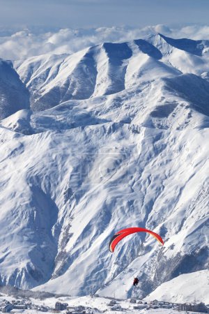 Foto de Velocidad de vuelo en las montañas nevadas sobre la estación de esquí en el soleado día de invierno. Montañas del Cáucaso. Georgia, región Gudauri. - Imagen libre de derechos