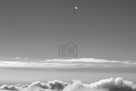 Foto de Cielo blanco y negro con nubes de luz solar y silueta de parapente en el día de invierno sol - Imagen libre de derechos