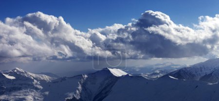 Téléchargez les photos : Vue panoramique sur les montagnes enneigées ensoleillées et ciel bleu avec nuages le soir d'hiver. Montagnes du Caucase, Géorgie, région Gudauri - en image libre de droit