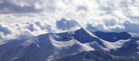 Foto de Vista panorámica del paracaidista en las montañas nubladas de la noche. Montañas nevadas del Cáucaso en invierno. Georgia, región Gudauri. - Imagen libre de derechos