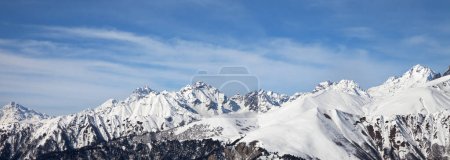 Foto de Montañas nevadas de luz solar y cielo azul con nubes en un día soleado. Montañas del Cáucaso en invierno. Georgia, región Svanetia. Vista panorámica. - Imagen libre de derechos