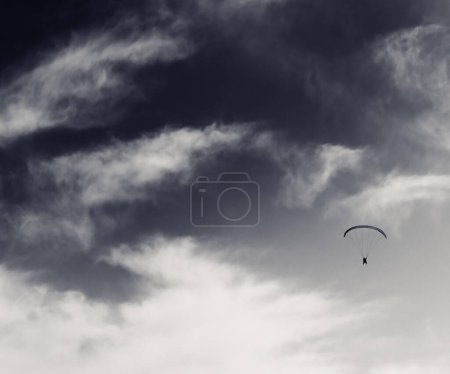 Foto de Silueta de paracaidista en el cielo ventoso. Imagen retro tonificada en blanco y negro. - Imagen libre de derechos