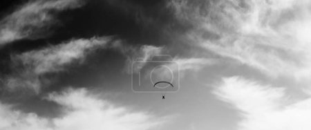 Foto de Vista panorámica de la silueta del paracaidista en el cielo ventoso. Imagen tonificada en blanco y negro. - Imagen libre de derechos