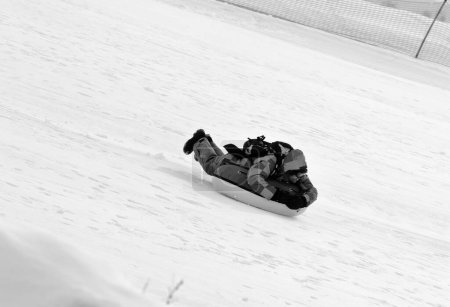 Foto de Snow tubing on ski resort at sunny day in snowy mountains. Winter vacation. Black and white toned image. - Imagen libre de derechos