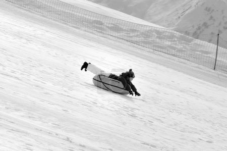 Foto de Niña cuesta abajo en el tubo de nieve en la estación de esquí en el día del sol en las montañas nevadas. Vacaciones de invierno. Imagen tonificada en blanco y negro. - Imagen libre de derechos