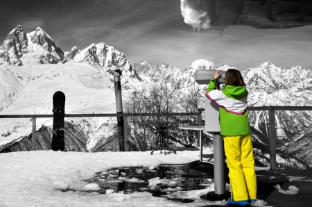 Foto de Chica mira a través de prismáticos en la plataforma de observación de la estación de esquí en la montaña de invierno en el día soleado. Montañas del Cáucaso. Svaneti región de Georgia. Monta Ushba. Efecto de color selectivo - Imagen libre de derechos