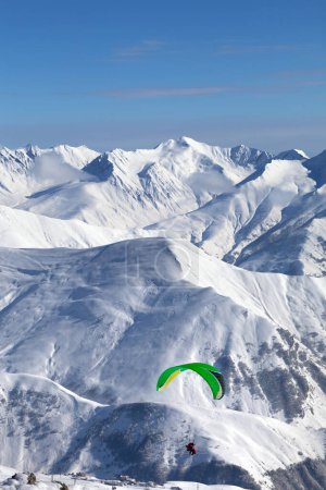 Foto de Parapente en las montañas nevadas sobre la estación de esquí en el día frío y soleado. Montañas del Cáucaso en invierno. Georgia, región Gudauri. - Imagen libre de derechos