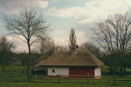 Foto de Pueblo ucraniano. Edificio vintage con techo de paja y valla de madera - Imagen libre de derechos